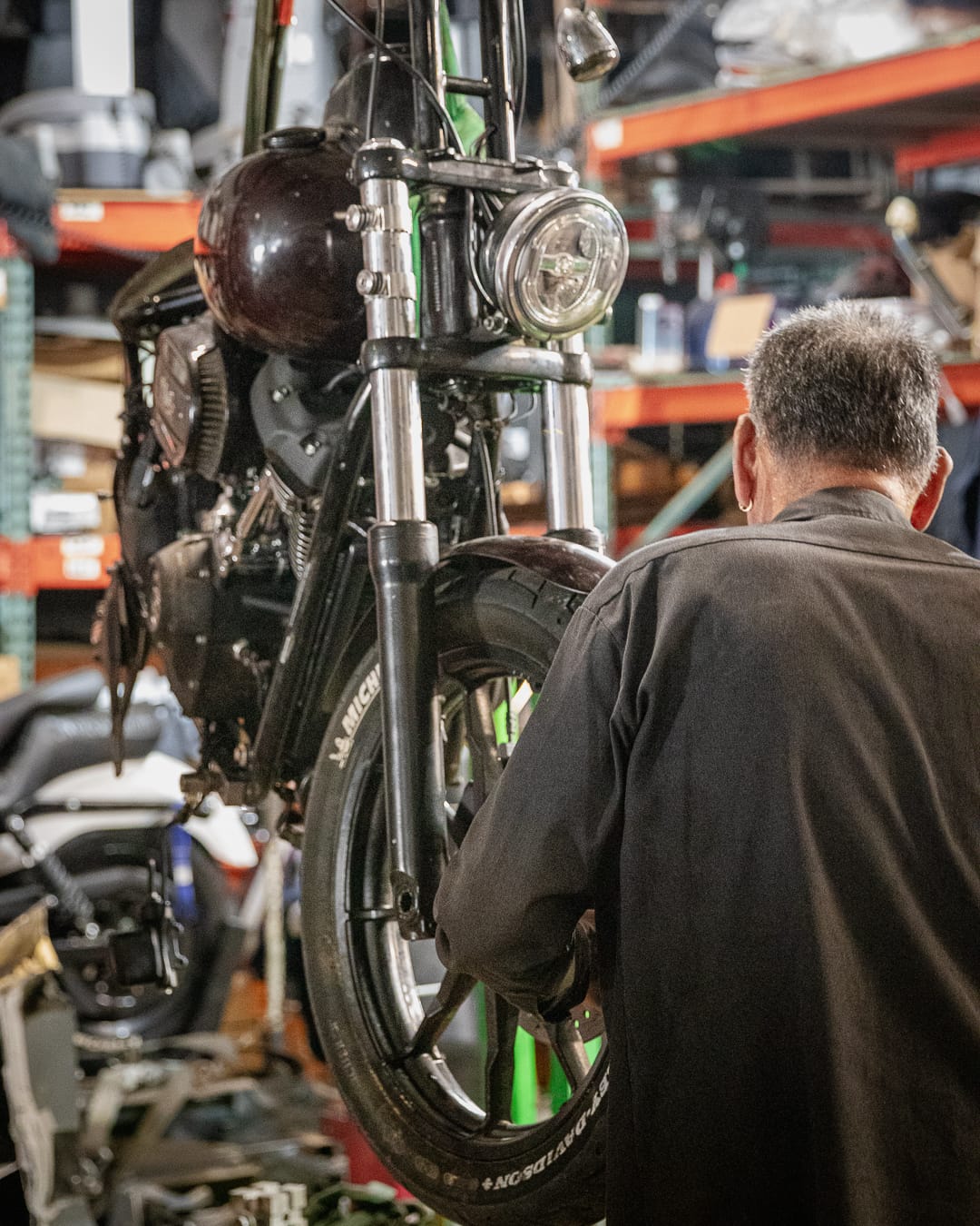 Technician inspecting a motorcycle front end and forks in the shop